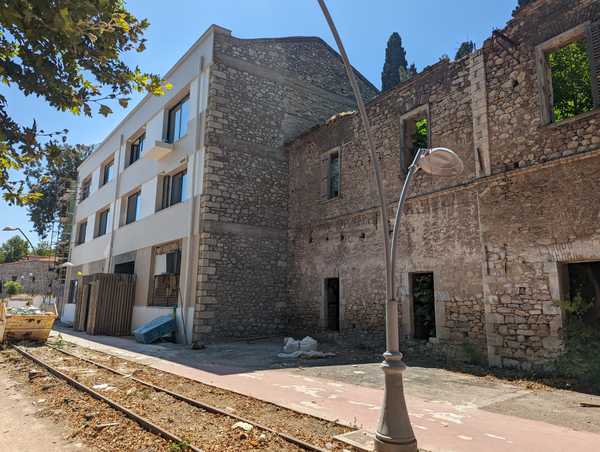 Two adjacent stone warehouses, one falling apart and the other with a new facade.