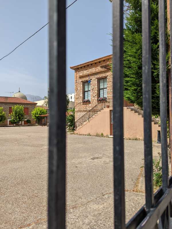 Old stone house, now a museum, partially seen through fence.